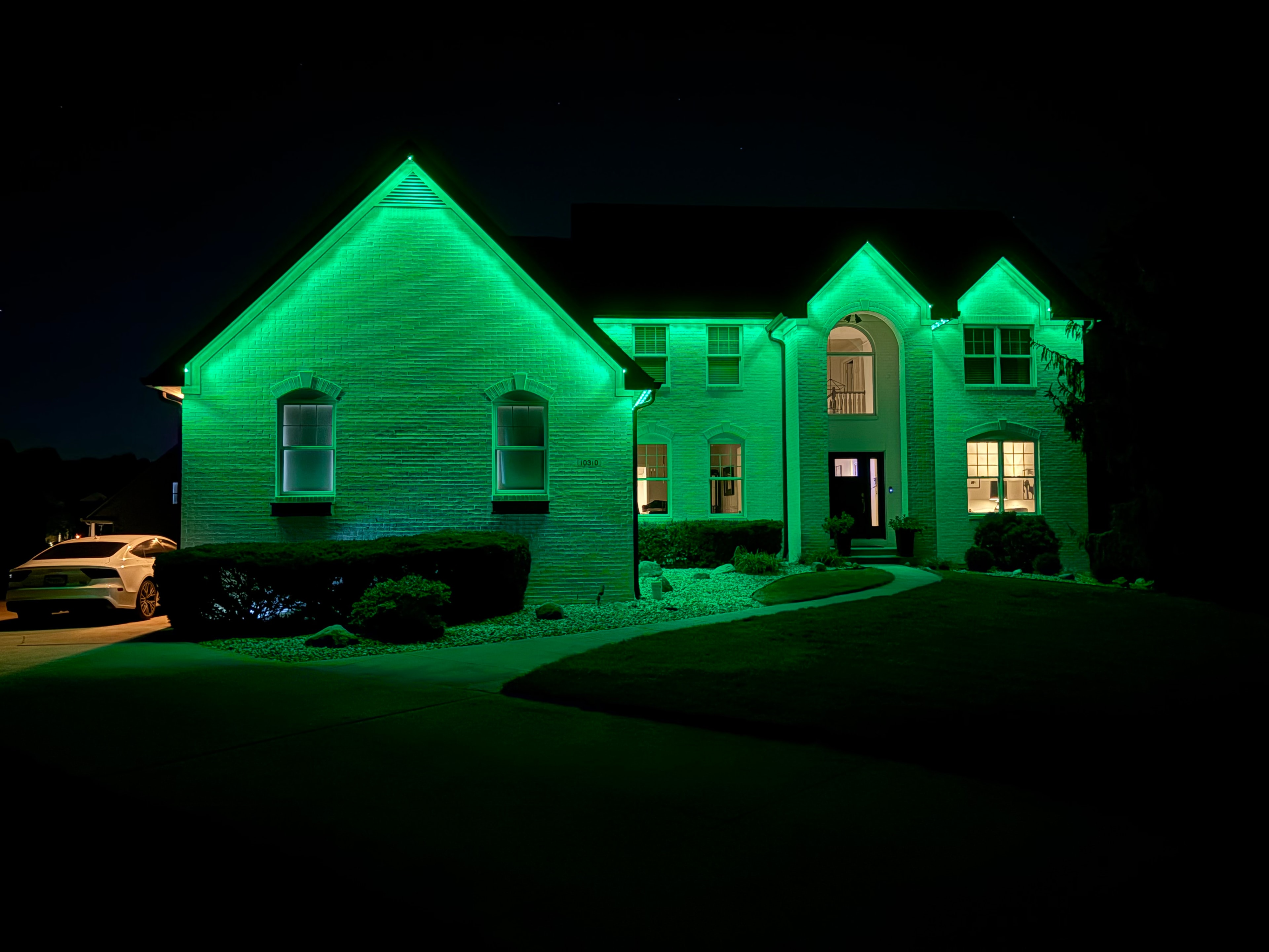 Home illuminated in green permanent LED roofline lighting